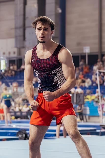 Young male gymnast celebrates with clenched fists, showing determination and intensity on the competition floor.