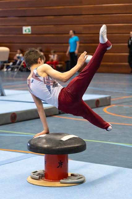 Young athlete demonstrates impressive balance on mushroom apparatus, executing a dynamic V-sit position during training session