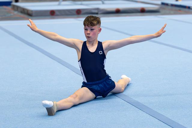 Young athlete performs floor routine with split position and extended arms during training session