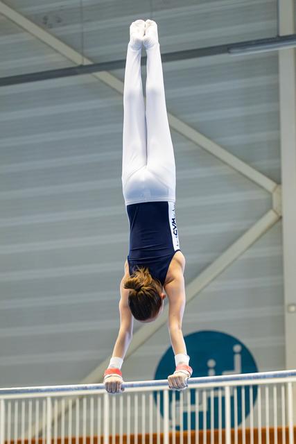 Young athlete performs perfect vertical handstand on parallel bars during indoor training session