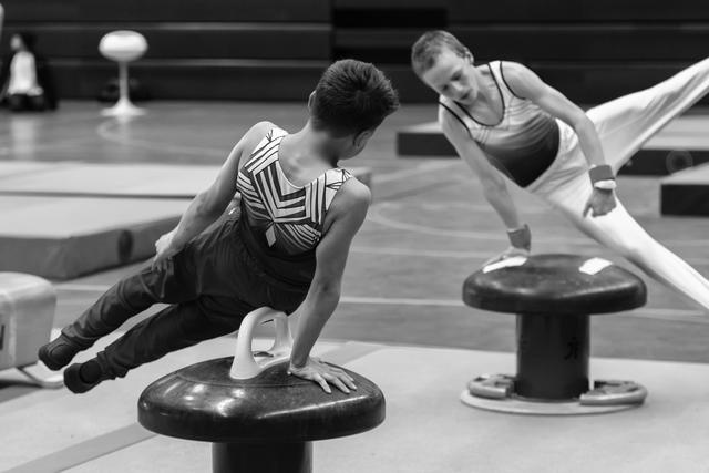 Two athletes perform plank exercises on mushroom trainers, demonstrating strength and form in black and white