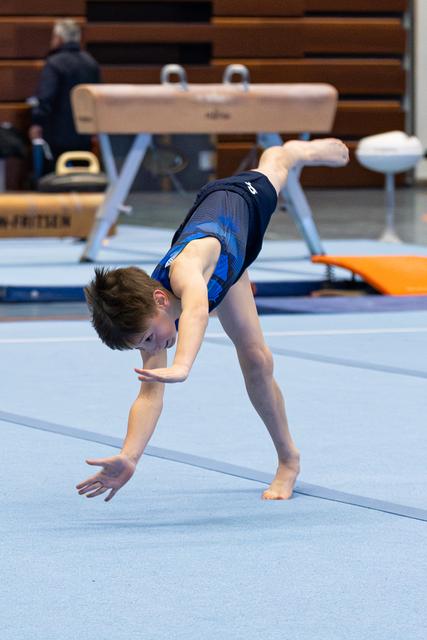Young athlete performs handstand walkover on floor exercise mat, demonstrating strength and flexibility during training