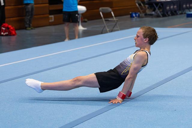 Young athlete performing an upward plank position on floor mat, displaying strength and focus during training