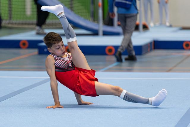 Young athlete performing a side balance during floor routine, demonstrating strength and flexibility at indoor sports facility