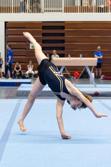 Young athlete mid-cartwheel on floor mat, displaying flexibility and form during routine at indoor sports venue