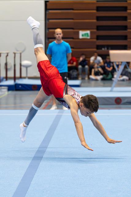 Young athlete executes a dynamic handstand during floor exercise, legs split in mid-air, showcasing flexibility and control
