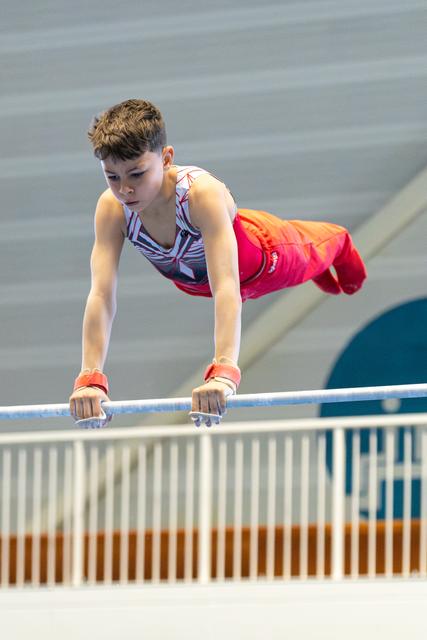 Young athlete holds a horizontal position on the bar, demonstrating strength and concentration during outdoor training