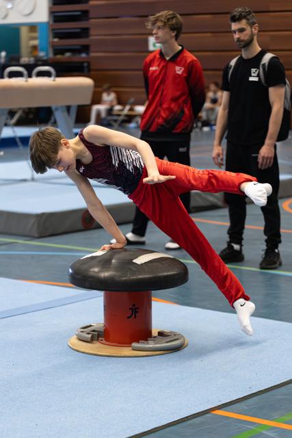 Young athlete demonstrates impressive strength on mushroom circle apparatus while coaches observe during training session