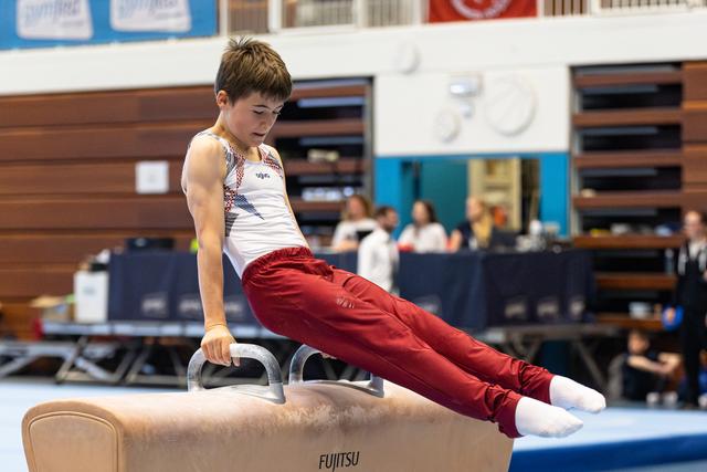 Young gymnast executes a L-sit position on pommel horse, displaying strength and control during training session