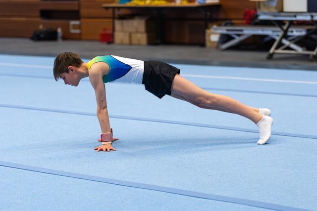 Young athlete holds a perfect plank position on hands on blue training mat, demonstrating core strength and body control