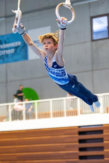 Athlete performing an impressive still rings routine, suspended in mid-air with perfect form during training