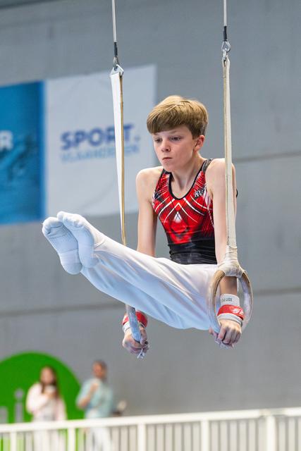 Young athlete performing a horizontal hold on still rings, displaying intense focus and controlled body position during routine