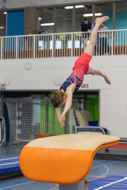 Young gymnast executes a handstand on the vault, demonstrating strength and balance during training at an indoor facility.