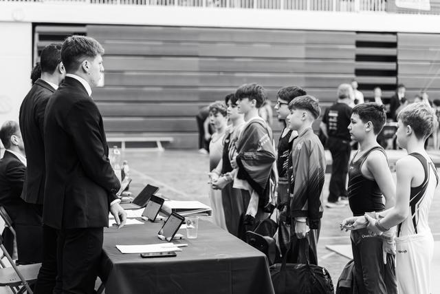 Gymnasts line up at awards table as officials prepare to distribute medals and recognition in gymnasium