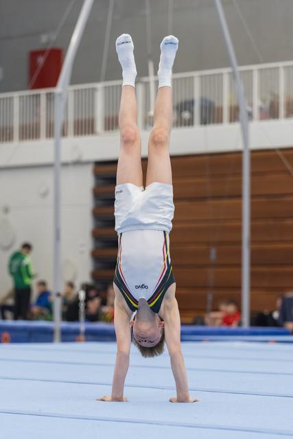 Young gymnast performs a controlled handstand on floor exercise mat in indoor training facility