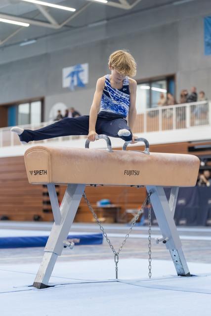 Young gymnast performs a horizontal hold on pommel horse, demonstrating strength and concentration in training facility