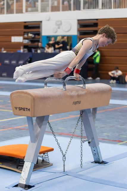 Young male gymnast performs a planche hold on pommel horse, displaying strength and control during training session.