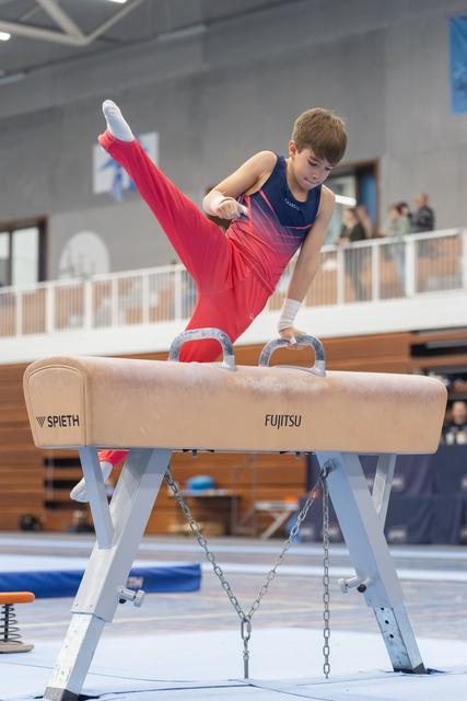 Young gymnast performs a leg extension on pommel horse, demonstrating strength and flexibility in a training facility