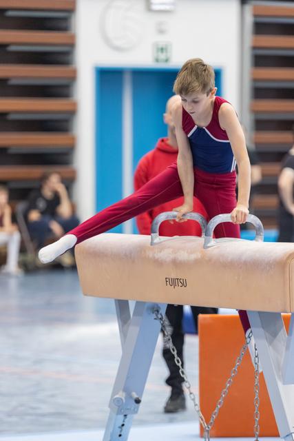 Young gymnast performs a side extension on pommel horse, demonstrating strength and focus during his routine