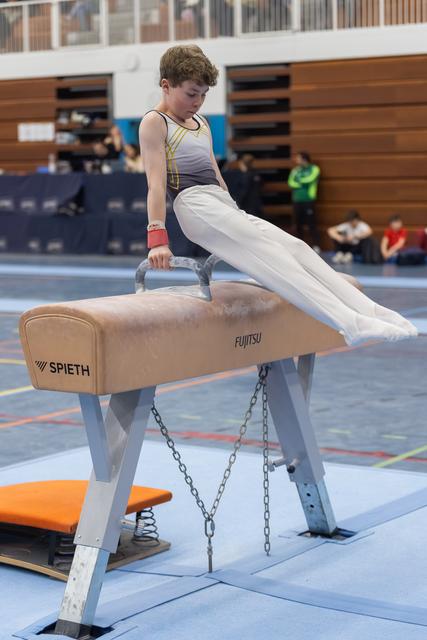 Young male gymnast performs a pommel horse routine with focused concentration in an indoor gymnastics facility