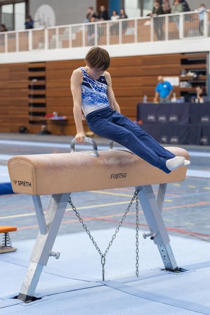 Young gymnast performs a side support position on pommel horse, demonstrating strength and technique during routine