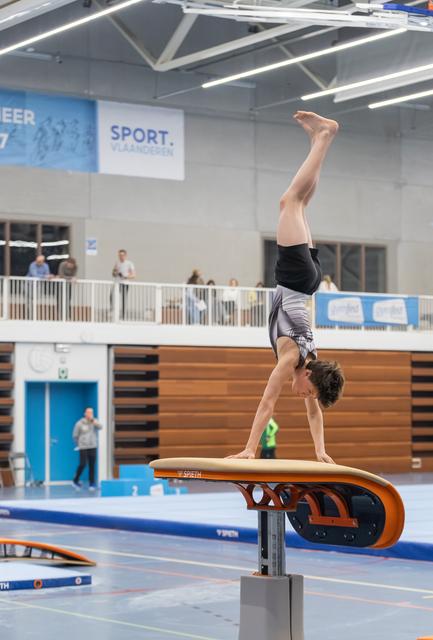 Gymnast performing a handstand on vault apparatus during training, demonstrating strength and balance in sports facility