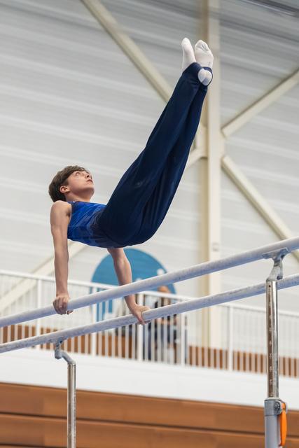 Young gymnast performing a handstand with extended legs on the horizontal bar during training