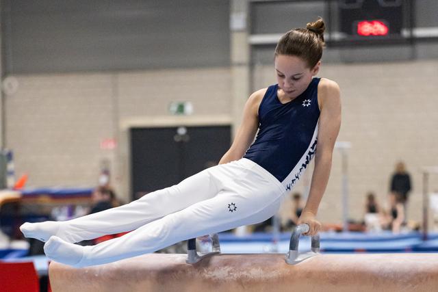 Young gymnast executes a horizontal support position on pommel horse, displaying focused concentration and strength