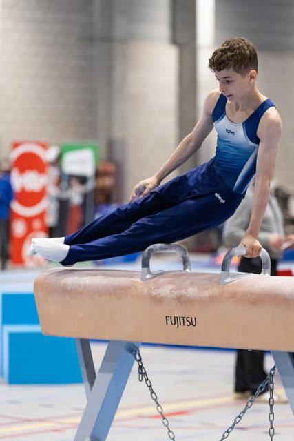 Young male gymnast executes a horizontal support position on pommel horse, displaying strength and concentration