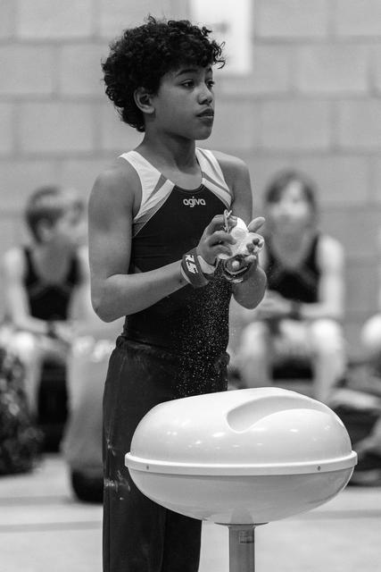 Young gymnast applying chalk to her hands while standing at the vault, focused expression before her routine