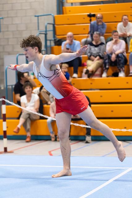 Young gymnast performs an artistic arabesque pose during floor routine, displaying focus and balance before spectators