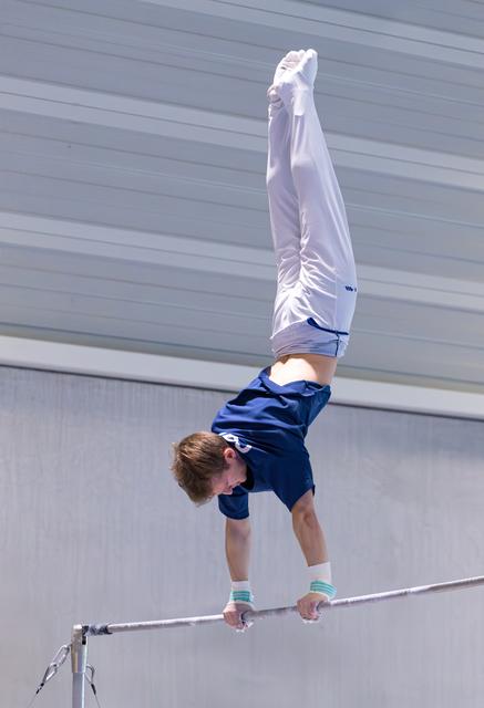 Young athlete performing an impressive handstand on the high bar during training, demonstrating strength and balance